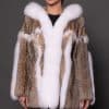Frontal view of a woman in a lynx fur coat with the hood down standing in front of a grey background.