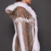 Profile view of a woman in a lynx fur coat with the hood down standing in front of a grey background. The woman is facing the right side of the frame.