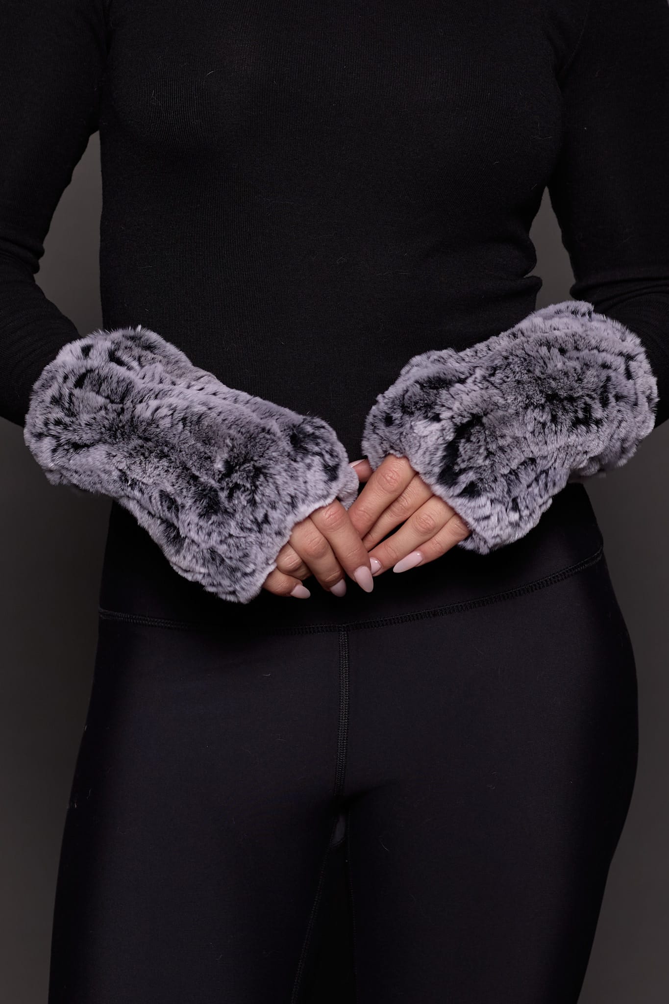 Image of a hands wearing grey knitted fur fingerless gloves