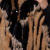 SASCHA REX KNIT BLACK DETAILS close up image of a woman in a black and brown fur knitted jacket against a grey background