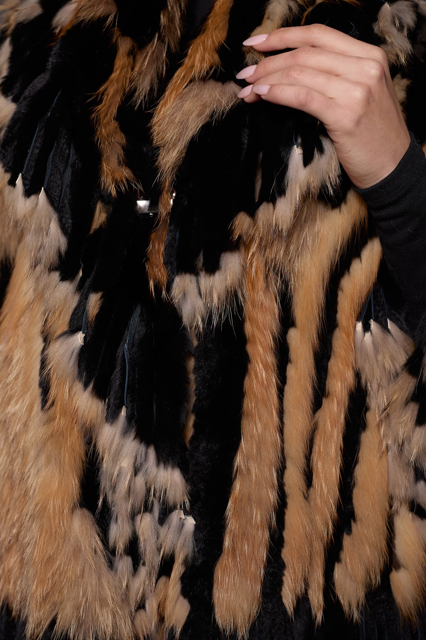 SASCHA REX KNIT BLACK DETAILS close up image of a woman in a black and brown fur knitted jacket against a grey background