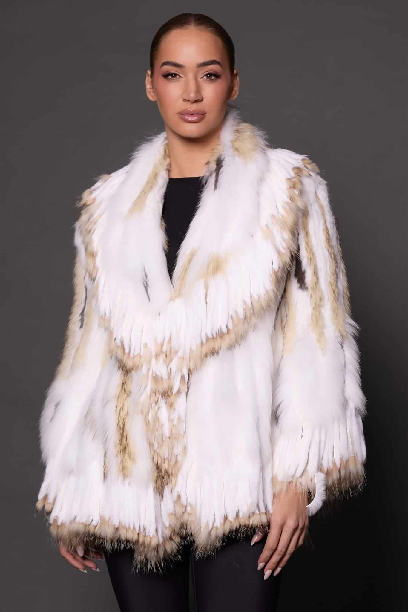 the front of a woman in a white fur knitted jacket against a grey background