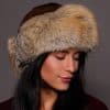 High angle frontal view of a woman in a mahogany mink fur and cross fox fur hat standing in front of a grey background.