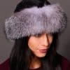 High angle frontal view of a woman in a ranch mink fur and indigo fox fur hat standing in front of a grey background.